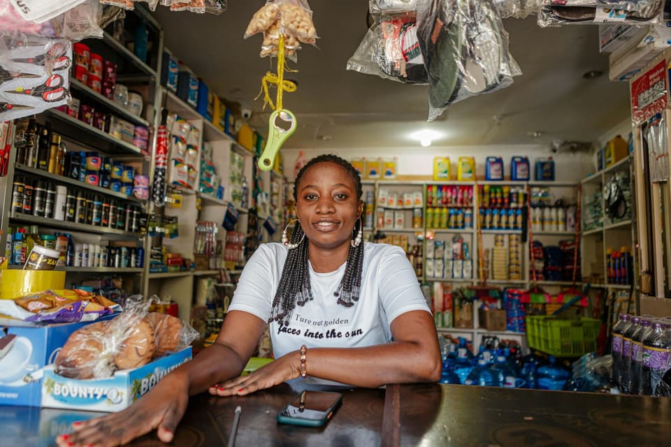 Une commerçante souriante derrière le comptoir de sa boutique